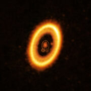 This image, taken with the Atacama Large Millimeter/submillimeter Array (ALMA), in which ESO is a partner, shows the young planetary system PDS 70, located nearly 400 light-years away from Earth. The system features a star at its centre, around which the planet PDS 70 b (highlighted with a solid yellow circle) is orbiting. On the same orbit as PDS 70b, indicated by a solid yellow ellipse, astronomers have detected a cloud of debris (circled by a yellow dotted line) that could be the building blocks of a new planet or the remnants of one already formed. The ring-like structure that dominates the image is a circumstellar disc of material, out of which planets are forming. There is in fact another planet in this system: PDS 70c, seen at 3 o’clock right next to the inner rim of the disc.